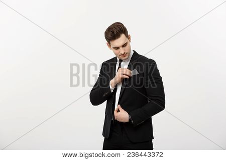 Business Concept: Businessman In Black Suit Picking Pasteboard Or Credit Card Out Of Pocket On Gray 
