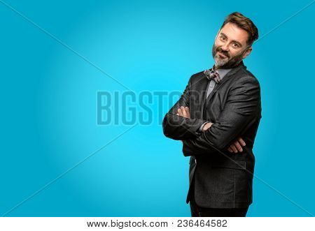 Middle age man, with beard and bow tie with crossed arms confident and happy with a big natural smile laughing