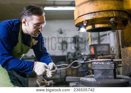 A Brutal Man Works In A Workshop, Forges Iron.