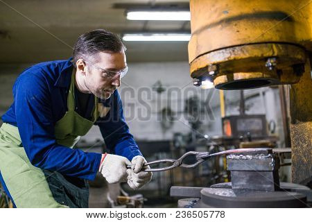 The Smith Works With An Electric Hammer.