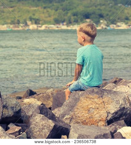Cute caucasian boy at seaside. Rear view. Leisure time