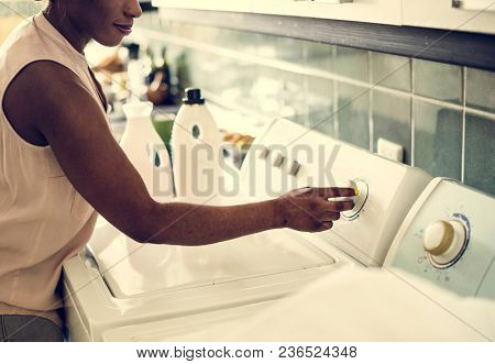 Black woman using washing machine doing the laudry