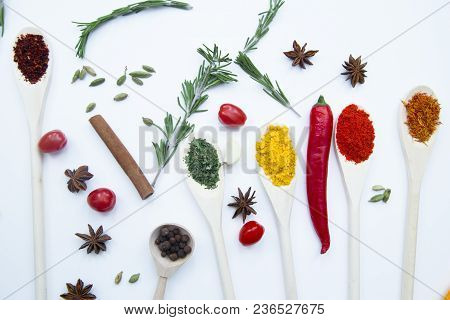 Cooking Hot Spicy Food Concept. Dry Spices And Herbs In Wooden Spoons, Fresh Herbs, Cloves And Cherr