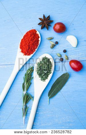 Cooking Hot Spicy Food Concept. Dry Spices And Herbs In Wooden Spoons, Fresh Herbs And Cherry Tomato