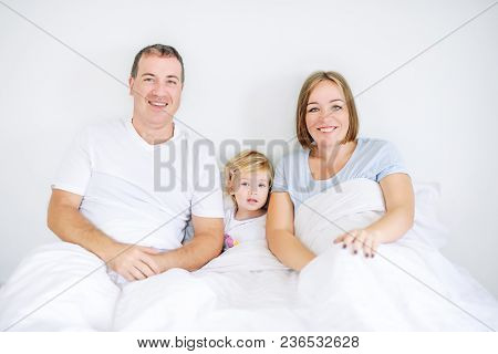 Portraits Of Happy And Loving Family In Sleepwear Looking At Camera In The Morning Time. Cheerful Pa