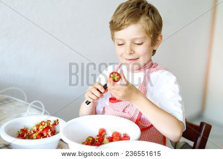 Little Blond Kid Boy Helping And Making Strawberry Jam In Summer. Funny Child Cleaning Berries And P