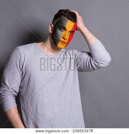 Portrait Of Pensive Man With The Flag Of Belgium Painted On His Face. Football Or Soccer Team Fan, S
