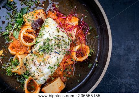 braised codfish filet and lettuce with calamarata noodles as top view on a plate