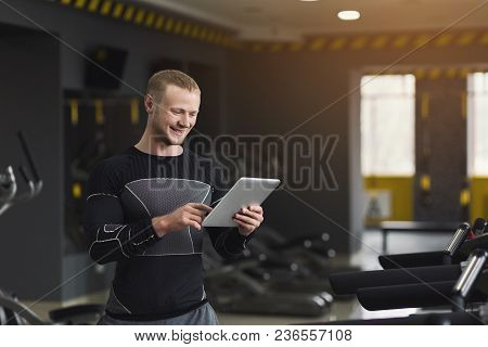 Athletic Young Man Texting On Digital Tablet Before Training At Gym, Using Application With Workout 