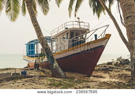Shipwreck On A Beach. Large Fishing Boat On The Sand On The Beach Under Palm Trees On The Indian Isl