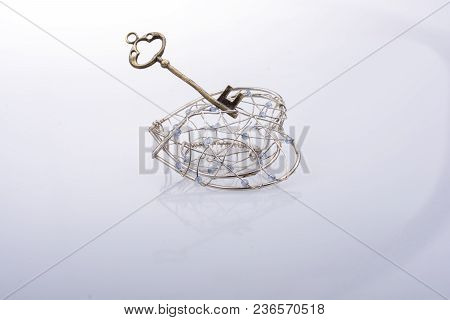 Key And A Heart Shaped Metal Cage On White