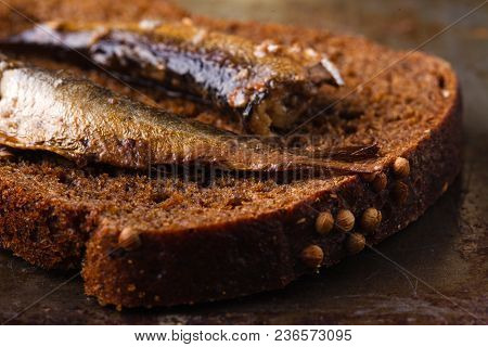 Canned Sprats In Tin Can With Rye Bread. On Rustic Background