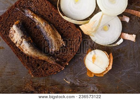 Canned Sprats In Tin Can With Rye Bread. On Rustic Background