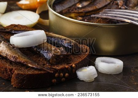 Canned Sprats In Tin Can With Rye Bread. On Rustic Background