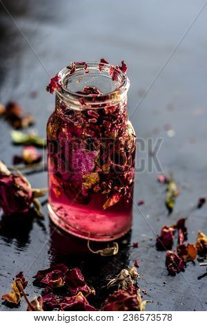 Close Up Of Extracted Rose Water Or Gulab Jal Or Gulab Ka Pani In A Transparent Bottle On Black Surf