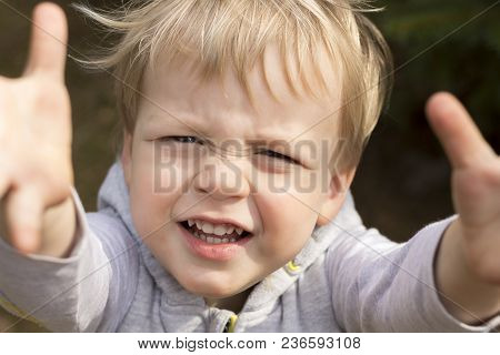 Sad Crying Toddler Pulls His Hands Up. Close Up Portrait Of Baby Boy Asking For Pick Up.