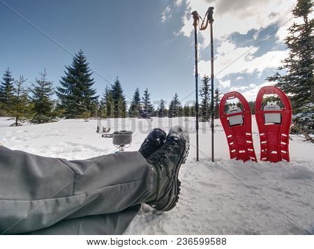Lunch Time During Winter Trail. Camping On Snow And Cooking. Red Snowshoes And Trekking Poles Stand 