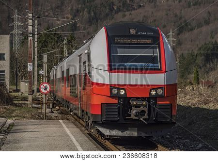 Red Electric Fast Train In Austria Alps Mountains In Sunny Spring Day
