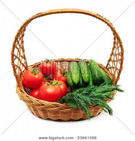 Pomodori e cetrioli in un cesto isolato su uno sfondo bianco.