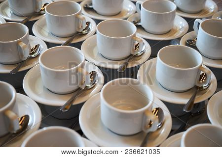 Set Of Empty White Ceramic Tea Or Coffee Cup And Saucers. Group Of Empty Cups Stacked In Rows For Se