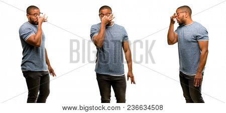 African american man with beard with sleepy expression, being overworked and tired, rubbes nose because of weariness