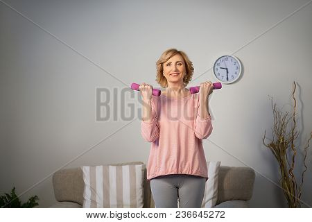 Happy Senior Woman Making Fitness Training With Dumbbells At Home.