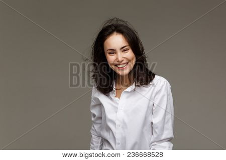 Beautiful Girl In A White Shirt Shows Emotions - Smile, Fun. On A Light Background.