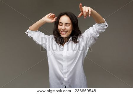 Beautiful Girl In A White Shirt Shows Emotions - Smile, Fun. On A Light Background.