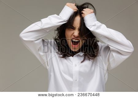 Beautiful Girl In A White Shirt Shows Emotions. On A Light Background.