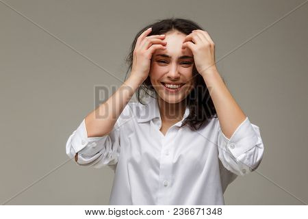 Beautiful Girl In A White Shirt Shows Emotions - Smile, Fun. On A Light Background.