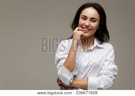 Beautiful Girl In A White Shirt Shows Emotions - Smile, Fun. On A Light Background.