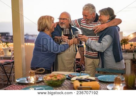 Senior Friends Having Fun Doing Barbecue Dinner In Terrace Outdoor - Mature People Dining And Laughi