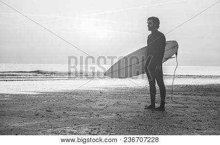 Male Surfer Standing On The Beach Waiting For Waves At Sunset Time - Man With Surfboard Wearing Wet 