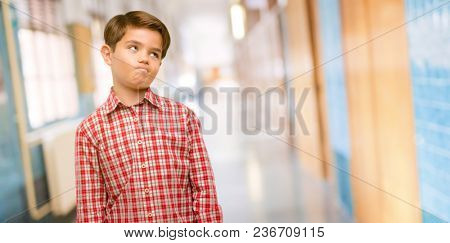 Handsome toddler child with green eyes making funny face fooling at school corridor
