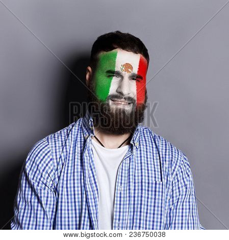 Face Of Young Bearded Man Painted With Flag Of Mexica. Football Or Soccer Team Fan, Sport Event, Fac