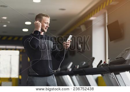 Young Man With Smartphone Before Running On Treadmill In Gym. Fitness Guy Jogging In Fitness Club, L