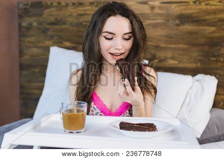 Girl With Coffee In Bed Eating A Cake