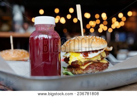 Burger and berry drink on restaurant table, high calorie junk food