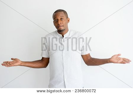 Puzzled African Man With Beard Shrugging Shoulders And Looking At Camera. Confused Frowning Handsome