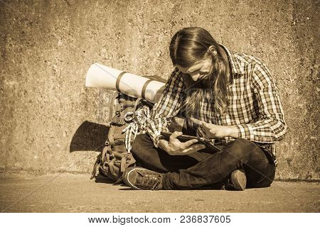 Man Tourist Backpacker Relaxing Outdoor Sitting By Grunge Wall Using Tablet. Internet, Tourism Activ