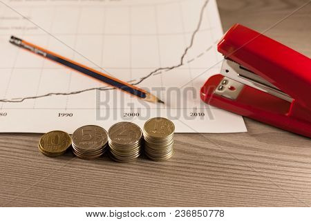 Stacks Of Money Coins With Graph Paper And Stapler