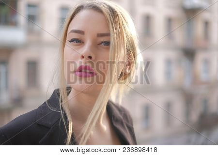 Portrait Of A Young Woman In A Black Suit Close-up Against A Background Of A Blurry City In The Rays