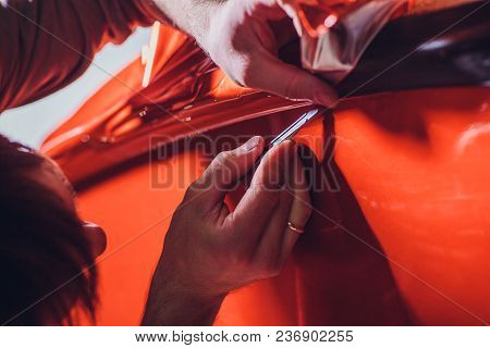 Car Wrapping Specialist Putting Vinyl Foil Or Film On Car. Selective Focus.