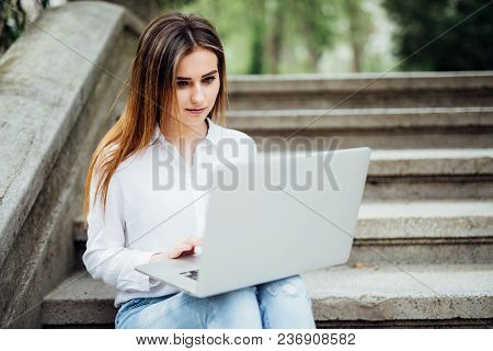 Smiling Student Girl Sitting On Stairs Working With Laptop, Preparing For Exams Outdoors, Having Res