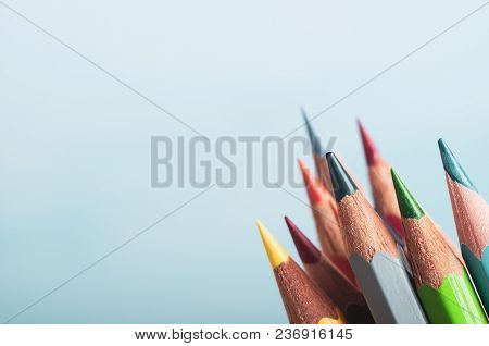 A Selection Of Art Pencils In Different Colours, Grouped At Lower Right Of Frame With Pale Blue Back