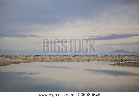 Water Reflection Mirrorowing The Soft Colours Of The Sky On Paarden Eiland Beach At Sunrise.