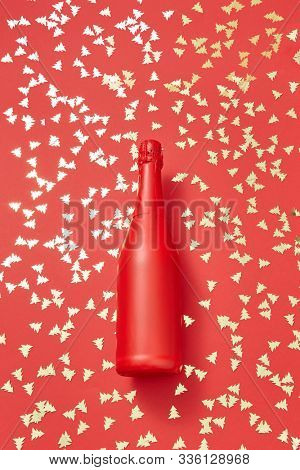 Christmas red painted champane bottle mock up on a holiday background covered shiny small spruces with copy space. Greeting holiday card.