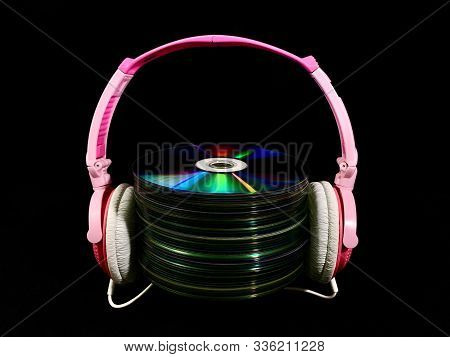 Stack Of Cds And Audio Headphones. Music Discs On A Black Background. Concept: Melomania.
