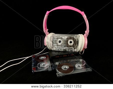 Plastic Cassette And Audio Headphones. Music Cassette On A Black Background. Concept: Music, Meloman