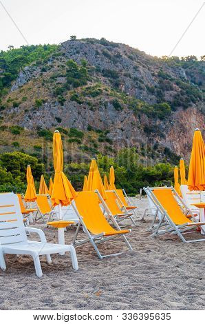 White Plastic And Metal Construction With Yellow Fabric Deckchairs Together With Yellow Umbrellas On